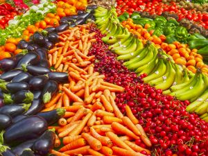 beautiful vibrant product: eggplants, carrots, strawberries, bananas and more laid out.