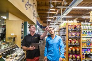 two men in a grocery store pointing at lights